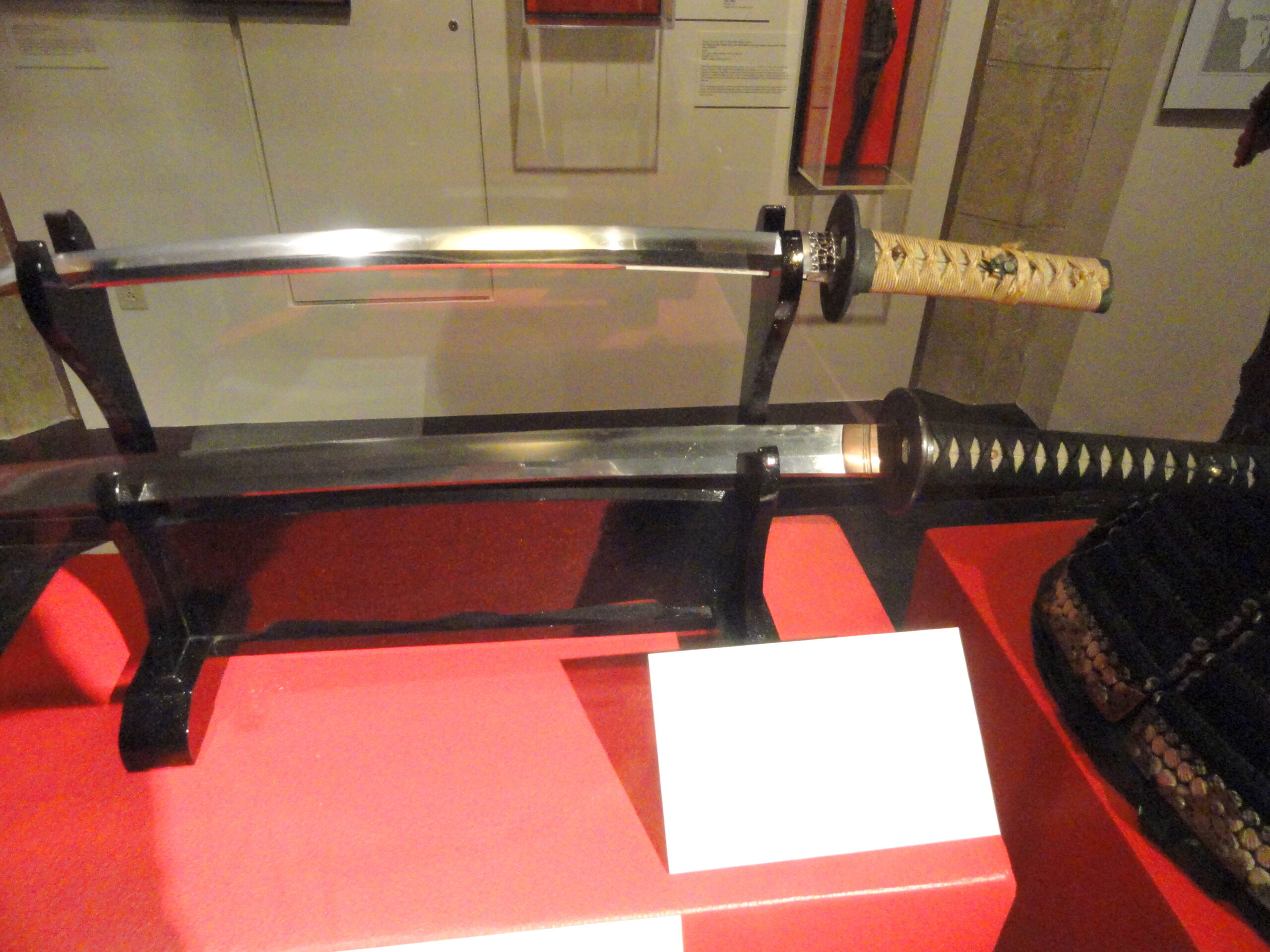 Meerdere Japanse zwaarden tentoongesteld op horizontale museumrekken in het Higgins Armory Museum, met katana, wakizashi en tachi uit verschillende perioden