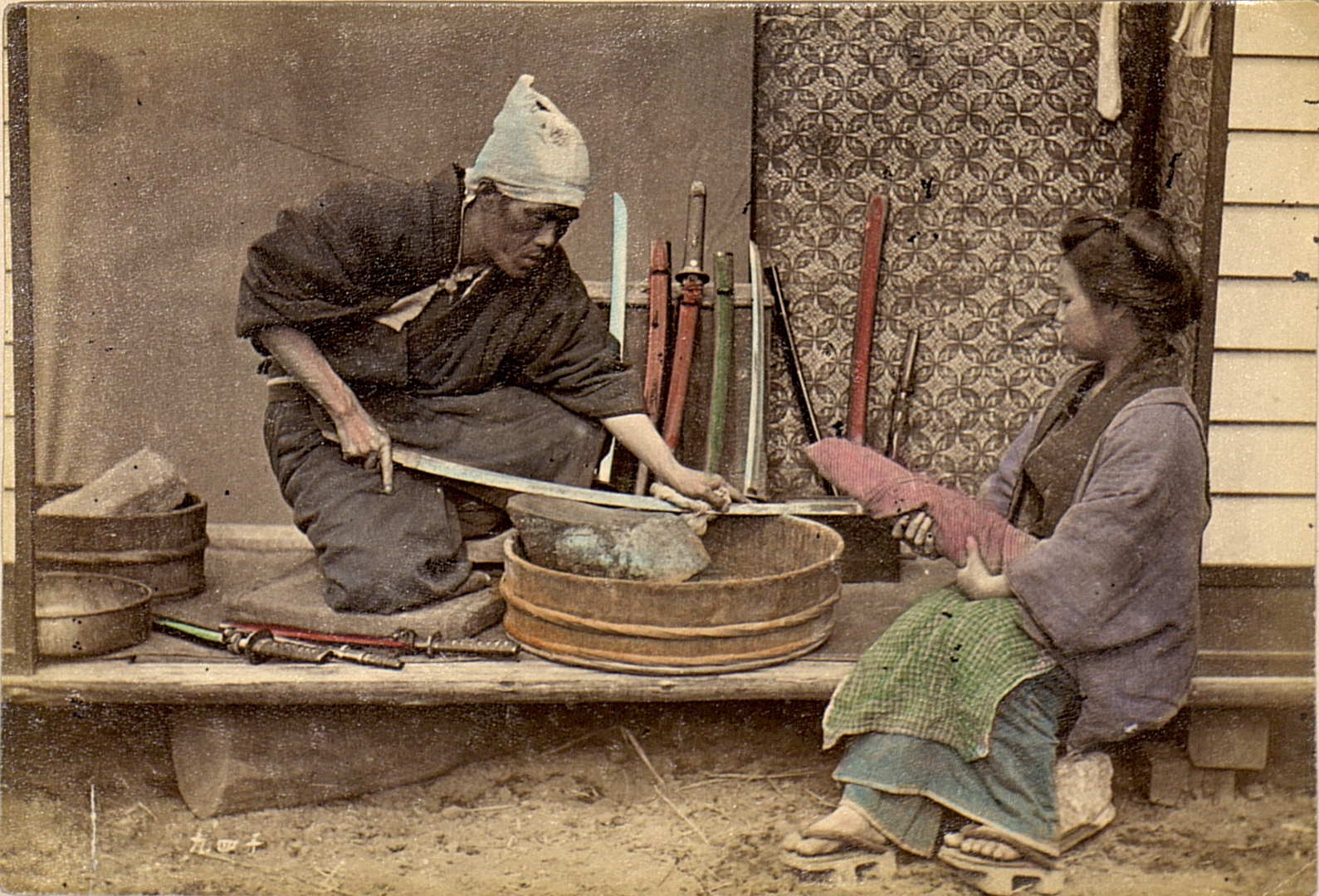 Een Japanse zwaardpoetser die een mes aan het slijpen is in 1909