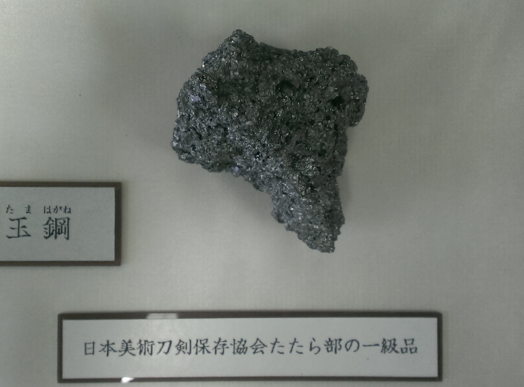 Een gebroken tamahagane stalen bloei die de kristallijne koolstofstructuur laat zien die wordt gebruikt om de kwaliteit van het Japanse zwaardsmeden te beoordelen